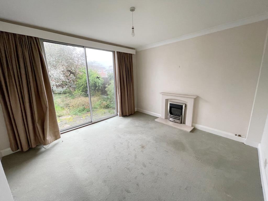 Lot: 63 - A DETACHED THREE-BEDROOM HOUSE SITUATED IN A POPULAR LOCATION FOR IMPROVEMENT - reception room with fireplace and patio doors to garden